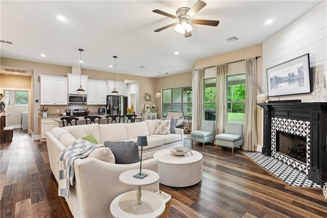 living room featuring plenty of natural light, ceiling fan, and dark wood-type flooring