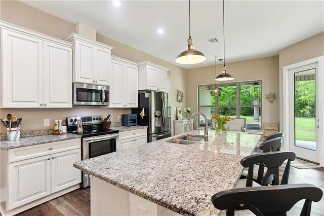 kitchen with stainless steel appliances, a sink, an island with sink, visible vents, and white cabinets