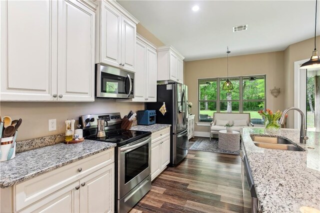 kitchen with white cabinets, a sink, stainless steel appliances, and dark wood finished floors