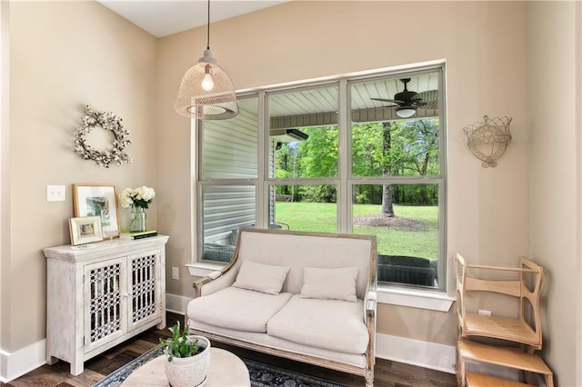 living area featuring baseboards, ceiling fan, and wood finished floors