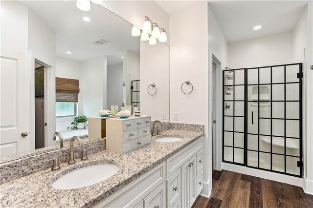 full bathroom with double vanity, visible vents, wood finished floors, and a sink