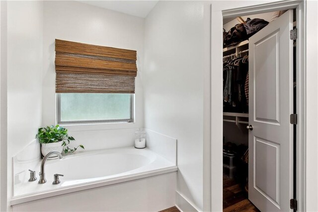 full bath featuring a garden tub and a spacious closet