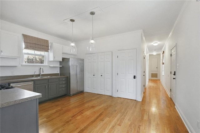 7464 Pitt St, New Orleans, LA 70118 - kitchen featuring stainless steel appliances, light wood finished floors, ornamental molding, pendant lighting, and white cabinetry