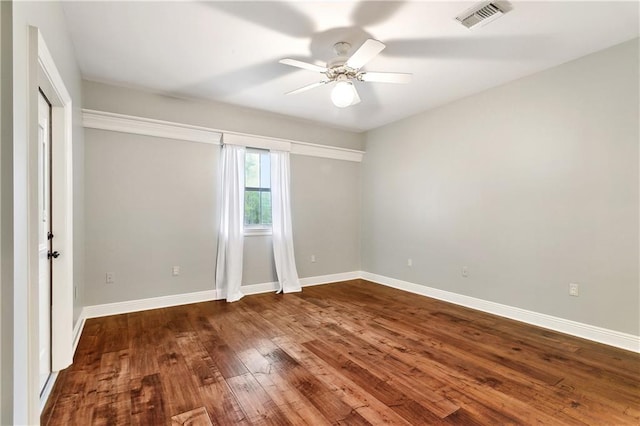 empty room with visible vents, ceiling fan, baseboards, and dark wood-style floors