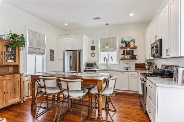 1217 N Tonti St, New Orleans, LA 70119 - kitchen with stainless steel appliances, a kitchen breakfast bar, open shelves, tasteful backsplash, and recessed lighting