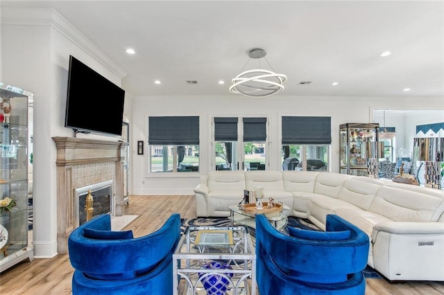 living area featuring a chandelier, crown molding, a fireplace, and wood finished floors