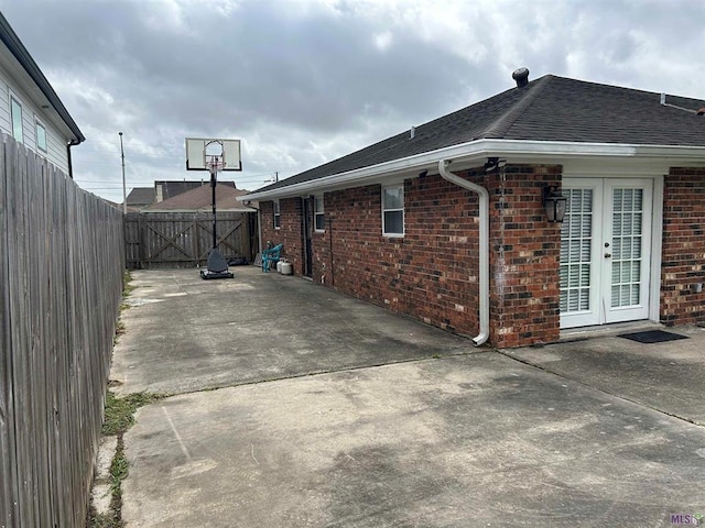 3404 Veronica Dr, Chalmette, LA 70043 - view of property exterior featuring brick siding, fence, a patio area, roof with shingles, and french doors