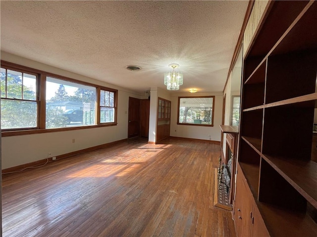 65 Willow Dr, Gretna, LA 70053 - interior space featuring an inviting chandelier, baseboards, a textured ceiling, visible vents, and wood finished floors