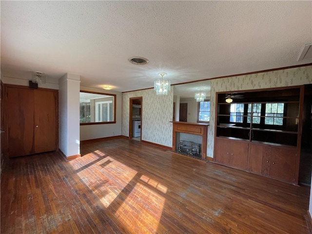 65 Willow Dr, Gretna, LA 70053 - unfurnished living room with a notable chandelier, hardwood / wood-style flooring, a textured ceiling, visible vents, and wallpapered walls