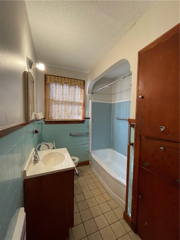 65 Willow Dr, Gretna, LA 70053 - full bath featuring tile patterned floors, wainscoting, tile walls, and a textured ceiling