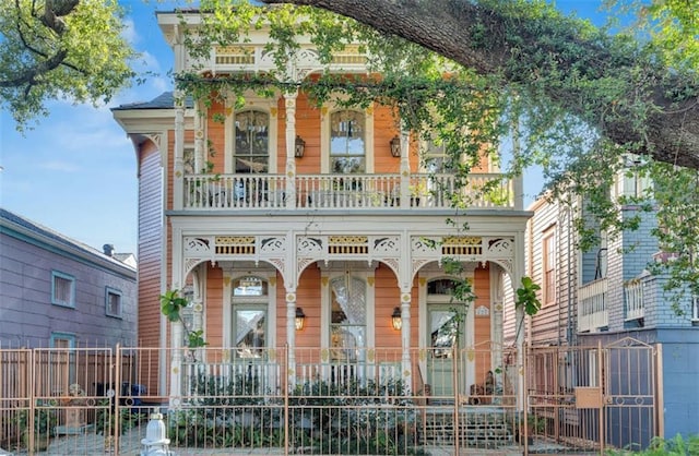 view of front of house featuring a balcony, a fenced front yard, and covered porch