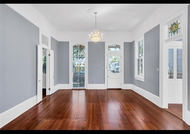 foyer entrance featuring baseboards, a notable chandelier, and wood-type flooring