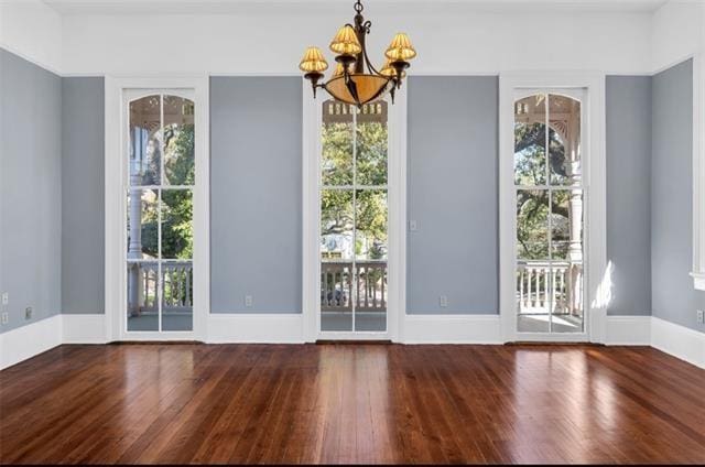interior space with baseboards, wood finished floors, and a chandelier