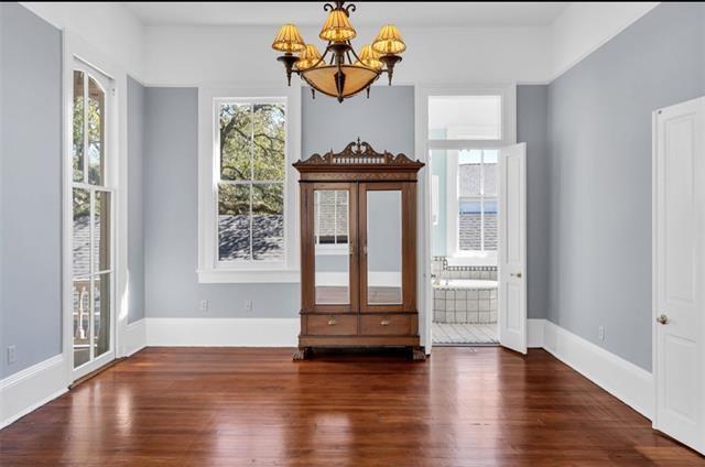 unfurnished dining area featuring baseboards, wood finished floors, and a notable chandelier
