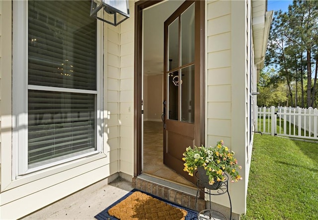 doorway to property with fence and a lawn