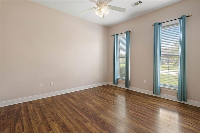 spare room featuring ceiling fan, wood finished floors, visible vents, and plenty of natural light