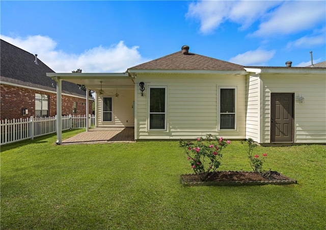 rear view of house featuring fence, a ceiling fan, a yard, and a patio