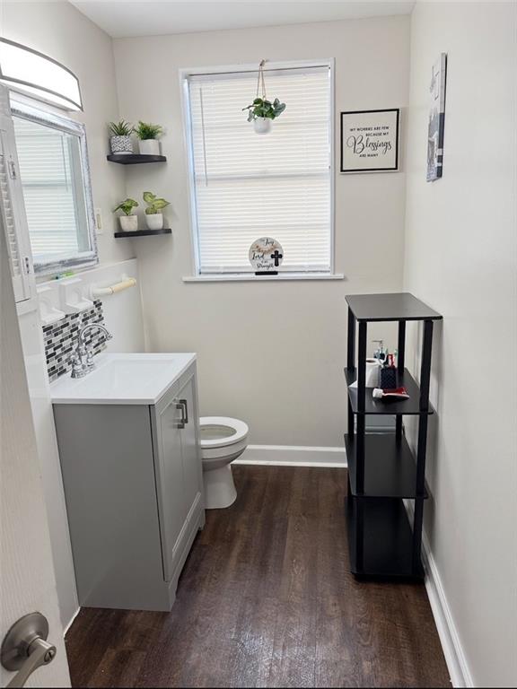 209 10th St, Bridge City, LA 70094 - half bathroom with baseboards, wood finished floors, vanity, and toilet