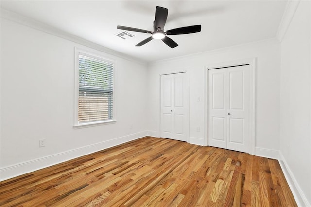3839 Johnson St, Metairie, LA 70001 - unfurnished bedroom featuring multiple closets, crown molding, light wood-style floors, baseboards, and ceiling fan