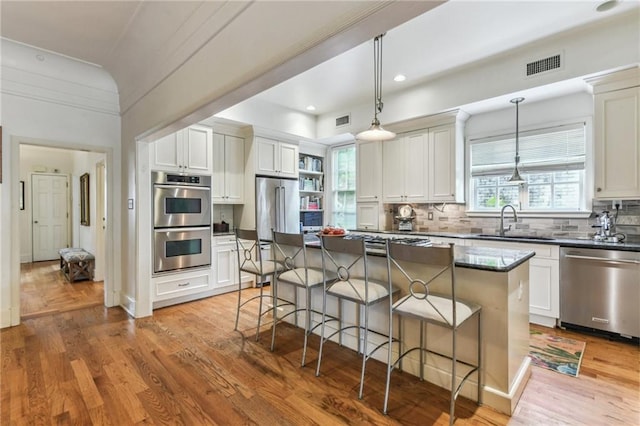 4209 Vendome Pl, New Orleans, LA 70125 - kitchen with a sink, a kitchen breakfast bar, appliances with stainless steel finishes, light wood-style flooring, and visible vents