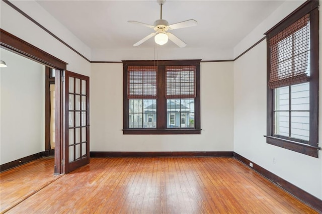 empty room featuring french doors, baseboards, light wood finished floors, and ceiling fan