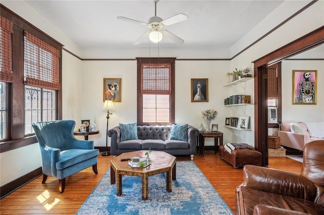 living room with a ceiling fan, baseboards, and wood finished floors