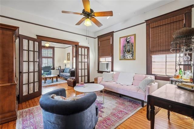 living area featuring cooling unit, wood finished floors, ceiling fan, and french doors
