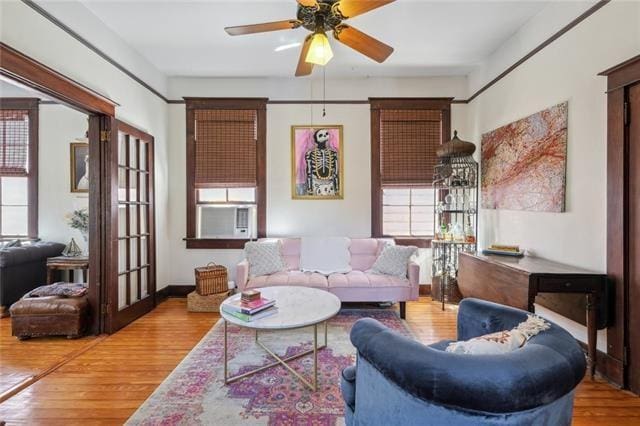 living room featuring baseboards, cooling unit, wood finished floors, and a ceiling fan