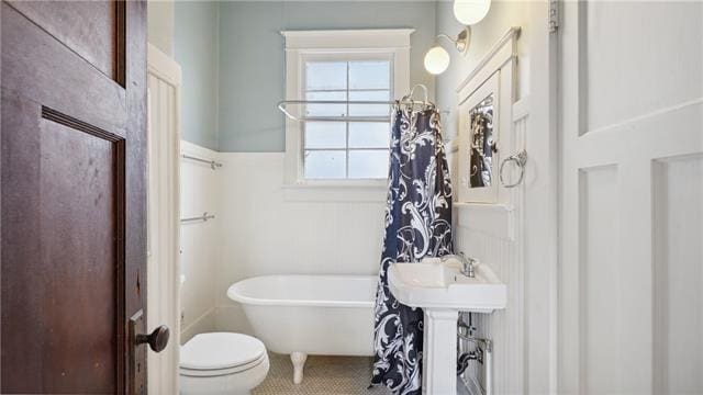 full bathroom featuring a tub, toilet, and tile patterned flooring