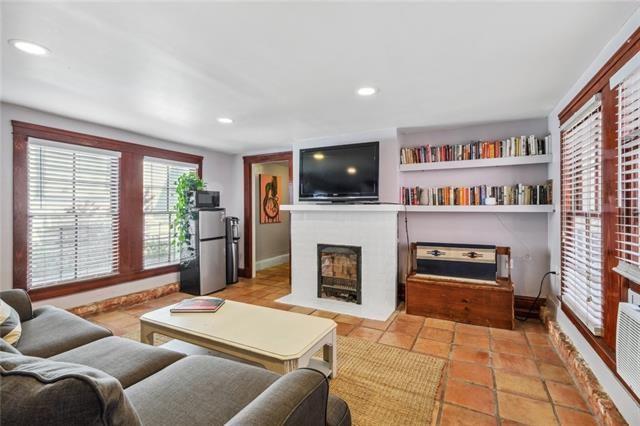 living room featuring a fireplace with flush hearth, baseboards, light tile patterned flooring, and recessed lighting