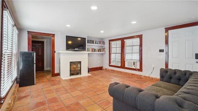 living area featuring cooling unit, recessed lighting, a fireplace with flush hearth, baseboards, and light tile patterned flooring