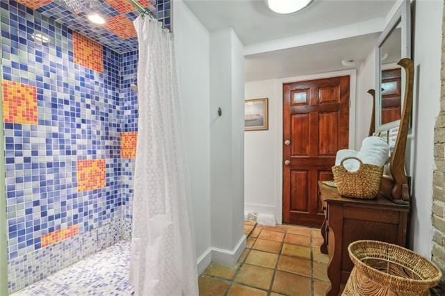 hall featuring light tile patterned flooring and baseboards
