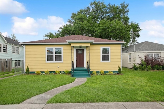bungalow-style house with fence and a front lawn