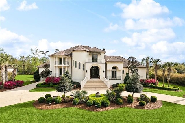 56 Preserve Ln, Mandeville, LA 70471 - mediterranean / spanish-style home featuring french doors, a balcony, curved driveway, and a front lawn