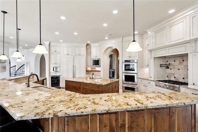 56 Preserve Ln, Mandeville, LA 70471 - kitchen with a sink, appliances with stainless steel finishes, a large island, arched walkways, and decorative backsplash