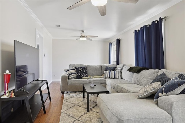 living room featuring visible vents, hardwood / wood-style flooring, baseboards, ornamental molding, and a ceiling fan