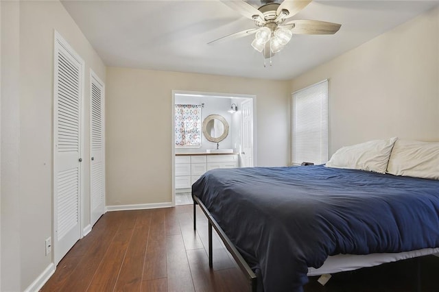 bedroom with a closet, a ceiling fan, dark wood-style floors, ensuite bathroom, and baseboards