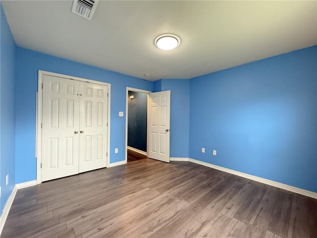 70281 7th St, Covington, LA 70433 - unfurnished bedroom with baseboards, visible vents, a closet, and wood finished floors
