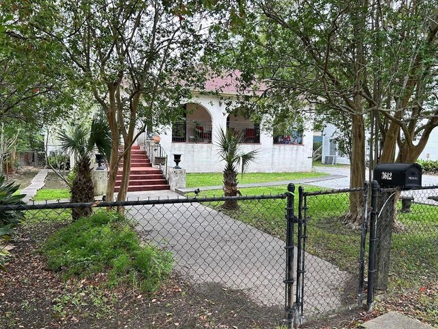 3612 Johnson St, Metairie, LA 70001 - view of property hidden behind natural elements with a gate, stucco siding, and stairs