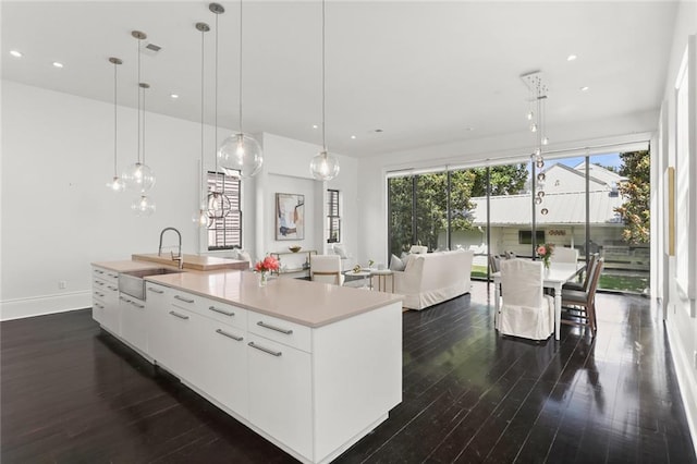 1035 Arabella St, New Orleans, LA 70115 - kitchen featuring a sink, dark wood-style flooring, a spacious island, light countertops, and hanging light fixtures