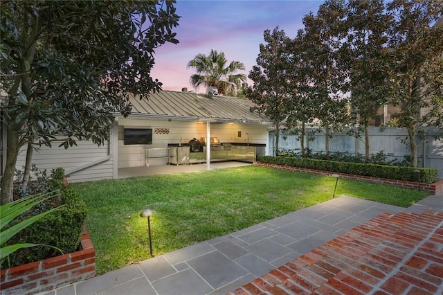 1035 Arabella St, New Orleans, LA 70115 - back of property at dusk with a patio, a lawn, metal roof, and a standing seam roof