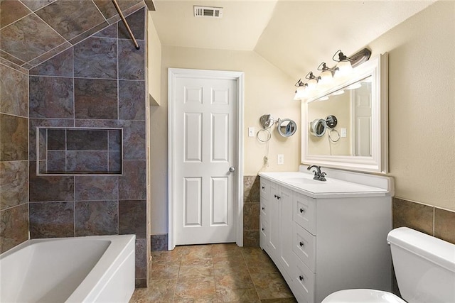 2106 Swan St, Slidell, LA 70460 - bathroom with tile walls, lofted ceiling, toilet, vanity, and shower / bath combination