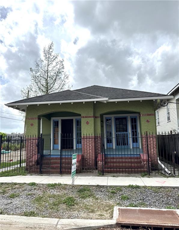 770002 Spruce St, New Orleans, LA 70118 - bungalow-style house featuring brick siding, a porch, a shingled roof, and fence