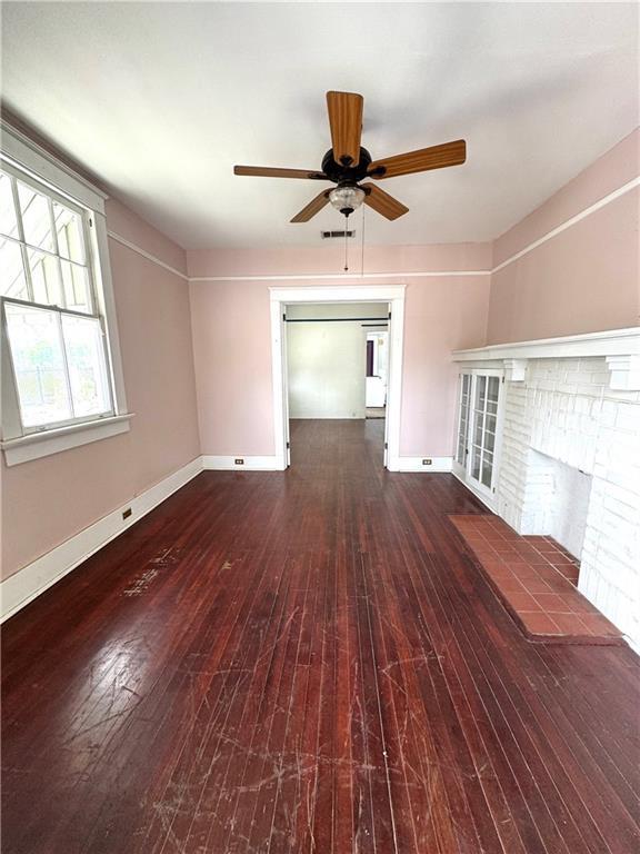 770002 Spruce St, New Orleans, LA 70118 - unfurnished living room featuring baseboards, a fireplace, a ceiling fan, and hardwood / wood-style flooring