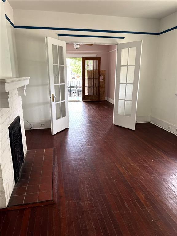 770002 Spruce St, New Orleans, LA 70118 - unfurnished living room featuring french doors, hardwood / wood-style floors, baseboards, and a fireplace
