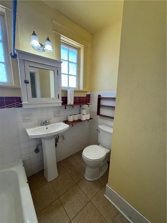 770002 Spruce St, New Orleans, LA 70118 - full bathroom featuring a wainscoted wall, tile patterned floors, toilet, a tub to relax in, and a sink