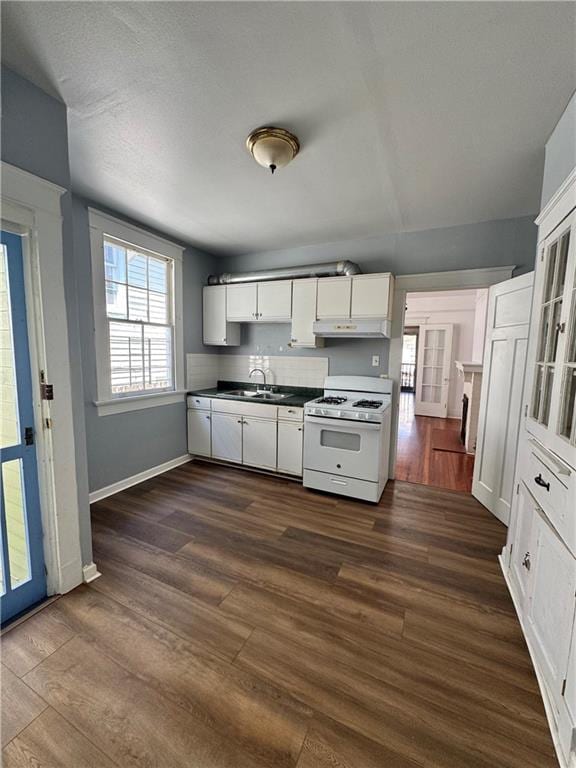 770002 Spruce St, New Orleans, LA 70118 - kitchen with white cabinetry, dark wood-style flooring, under cabinet range hood, dark countertops, and white gas range oven