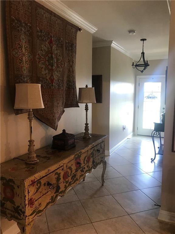 corridor featuring baseboards, ornamental molding, light tile patterned flooring, and an inviting chandelier
