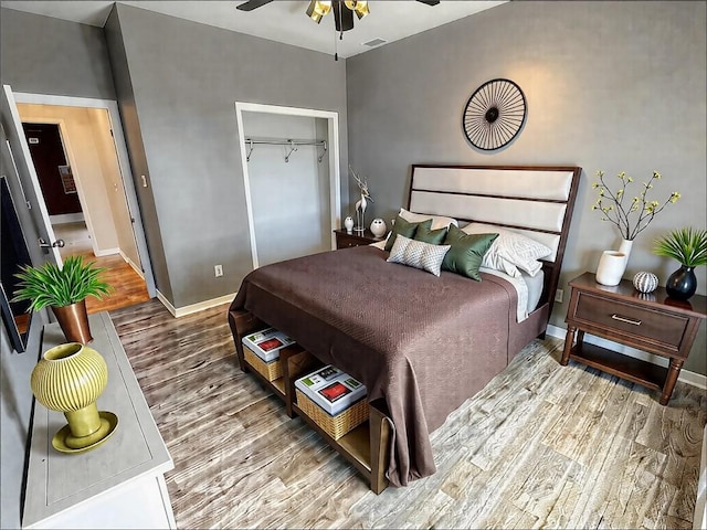 bedroom featuring wood finished floors, a closet, baseboards, and visible vents