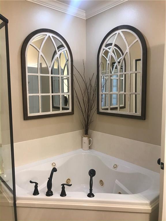 bathroom featuring crown molding and a tub with jets